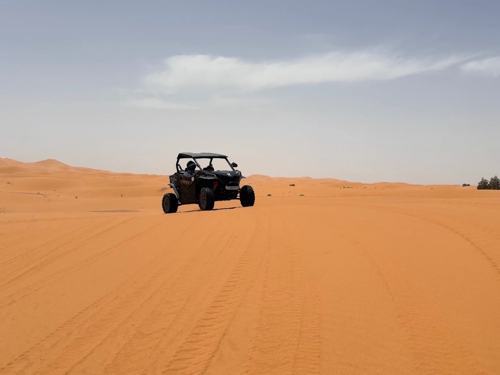 Dune buggy che attraversa la sabbia arancione liscia a Merzouga