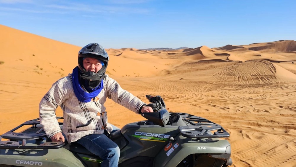 Piloto sonriente con casco en un quad durante una excursión de 1 hora por las dunas de Merzouga