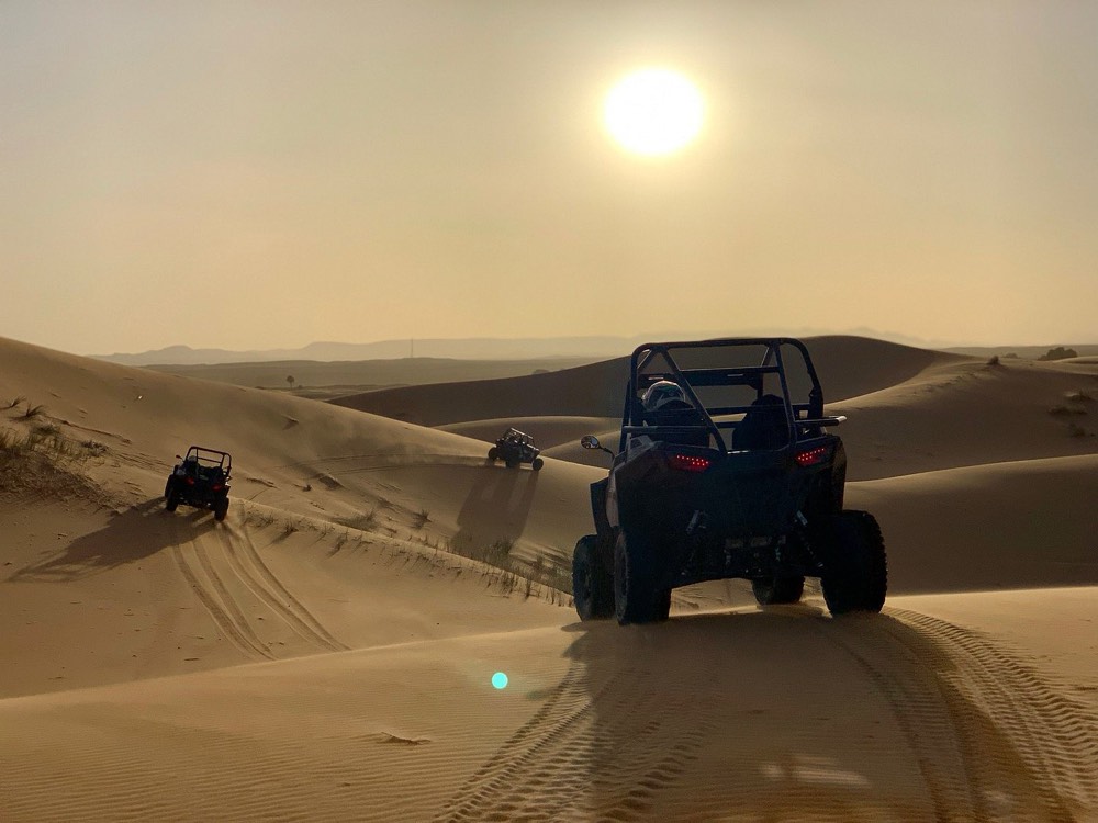 Duinbuggy rijdt onder de zon de duinen van de Erg Chebbi in