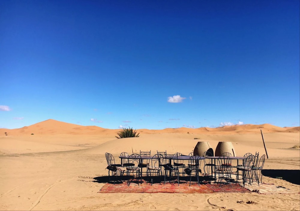 Gedeckter Essbereich im Sand mit den Dünen des Erg Chebbi im Hintergrund