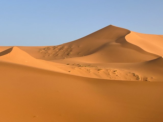 Hohe orangefarbene Sanddünen des Erg Chebbi unter klarem blauem Himmel