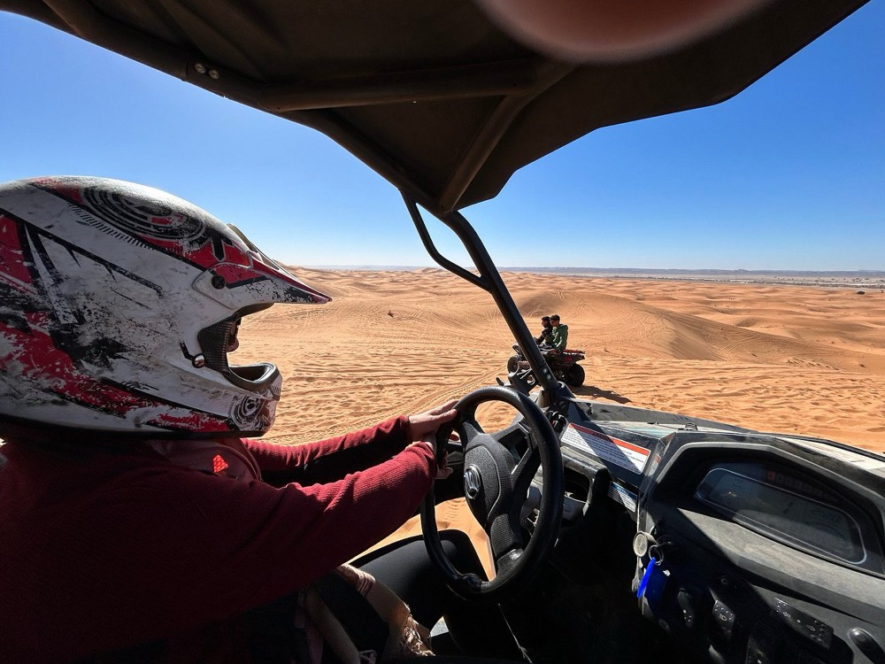 Fahrer mit Helm steuert einen Buggy durch die Dünen des Erg Chebbi