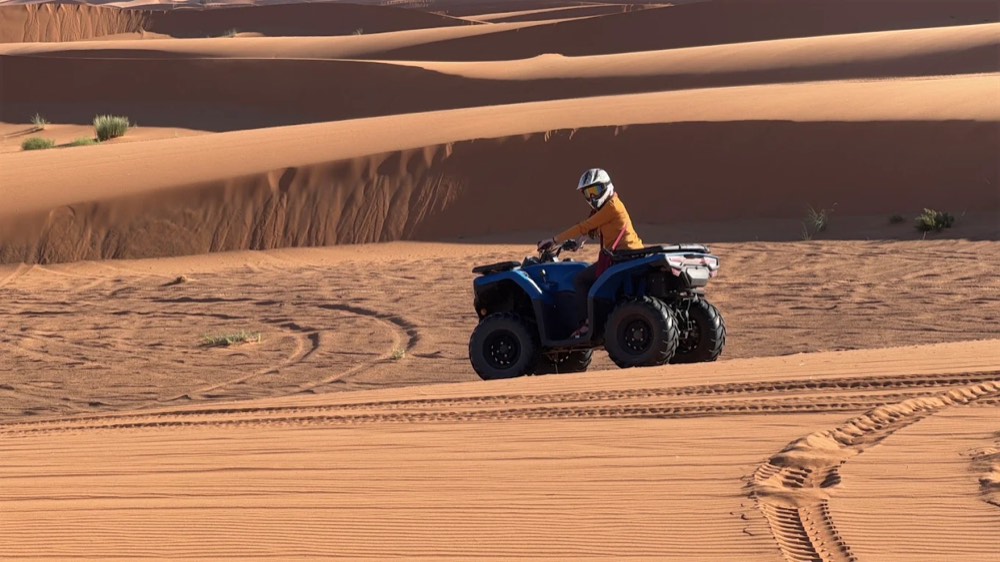 Pilota su un quad che attraversa le dune aperte dell’Erg Chebbi in una lunga escursione nel deserto