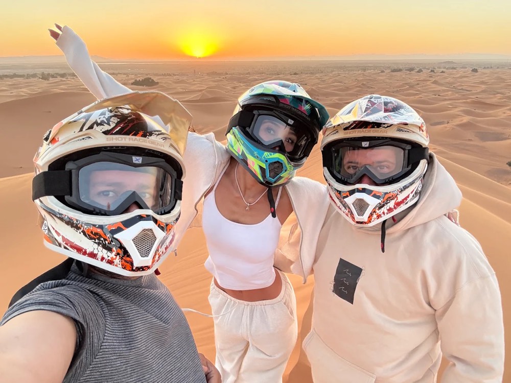 Friends in quad helmets taking a selfie at sunset in the Merzouga desert