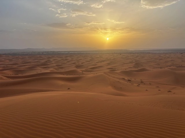 Sol baixo a brilhar sobre um mar de dunas no Erg Chebbi