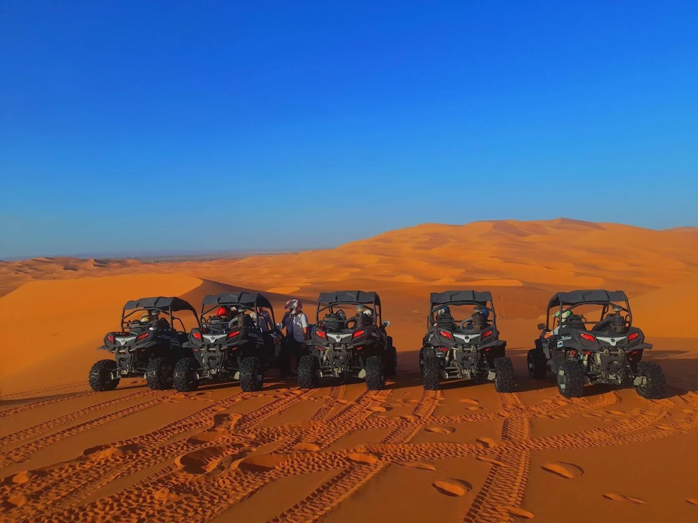 Cinque dune buggy in fila sulla sabbia davanti alle dune dell’Erg Chebbi