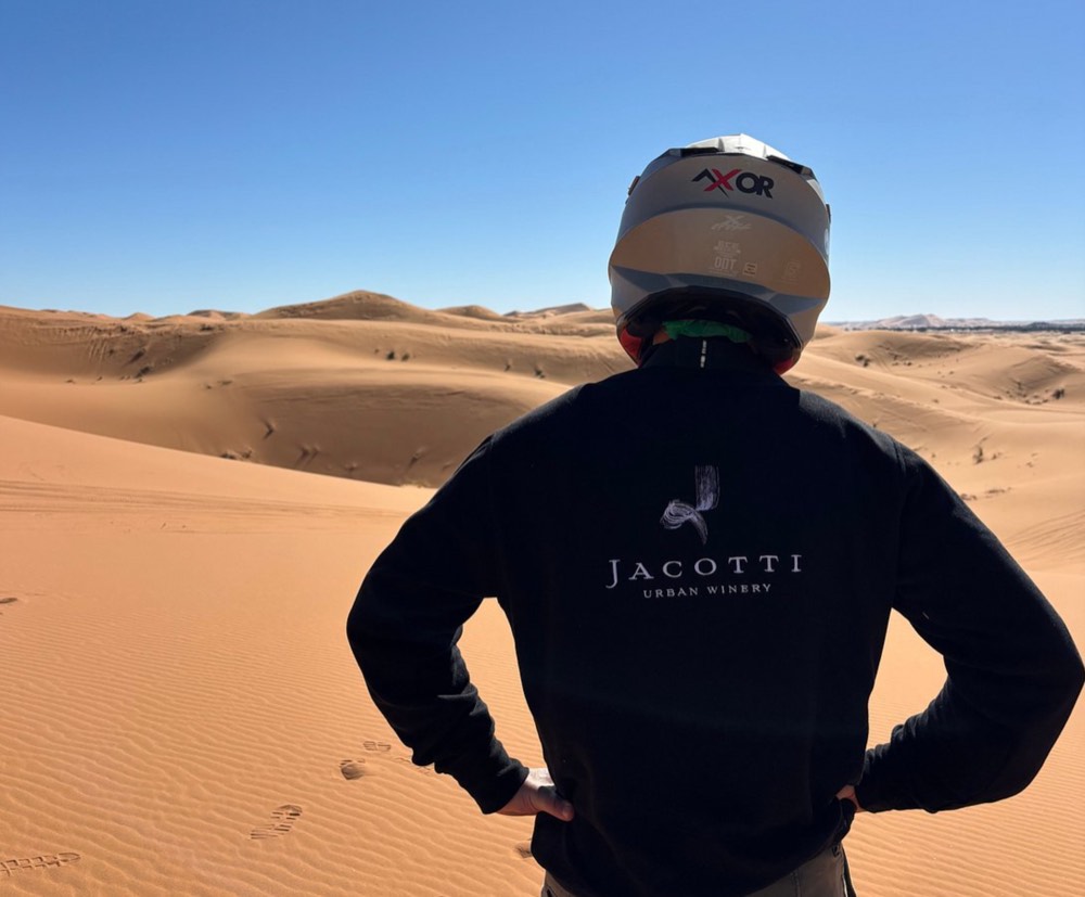 Pilota con il casco guarda le dune dell’Erg Chebbi prima di un’uscita