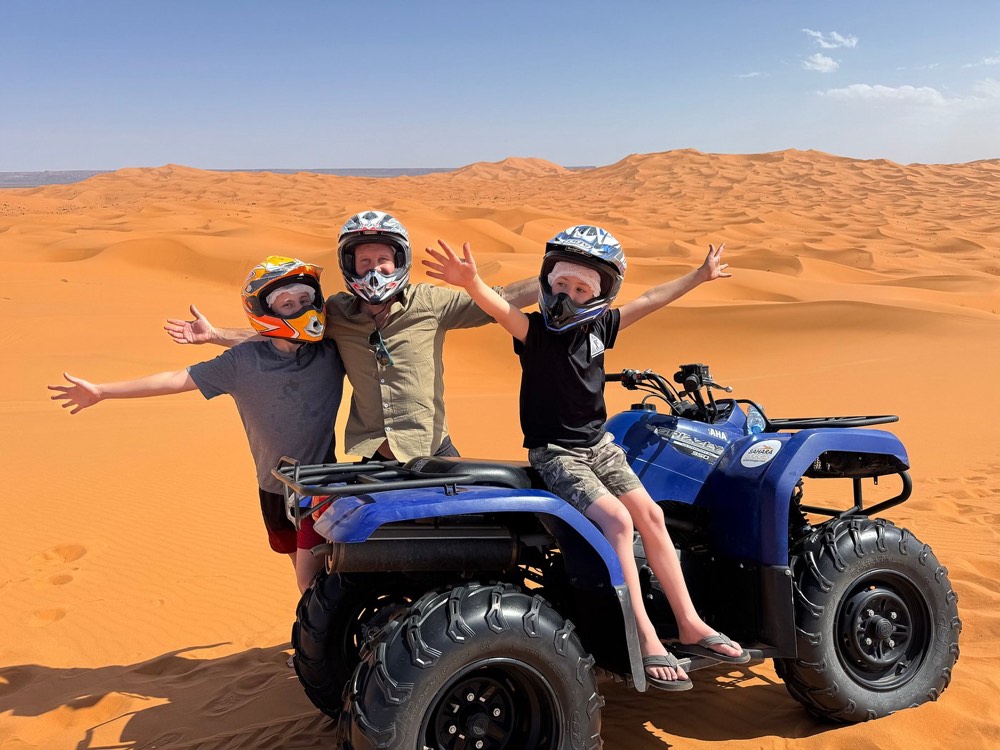 Family with children posing on a quad in the dunes of Merzouga