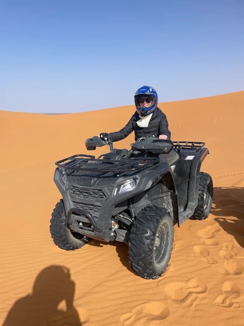 Fahrer mit Integralhelm auf einem schwarzen Quad im weichen Sand