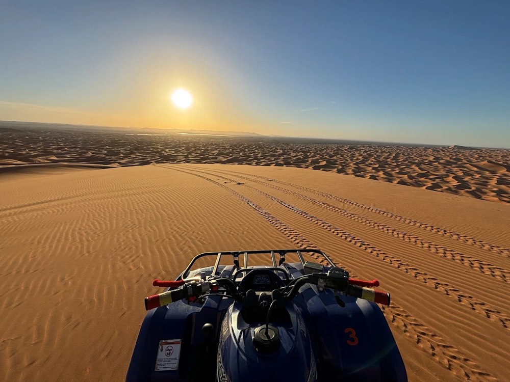 Vista sopra il manubrio del quad mentre il sole sorge sulle dune dell’Erg Chebbi