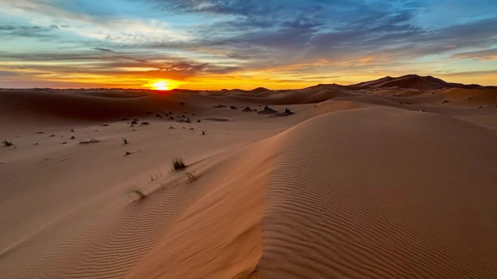 Sun setting behind rippled dunes in the Merzouga desert
