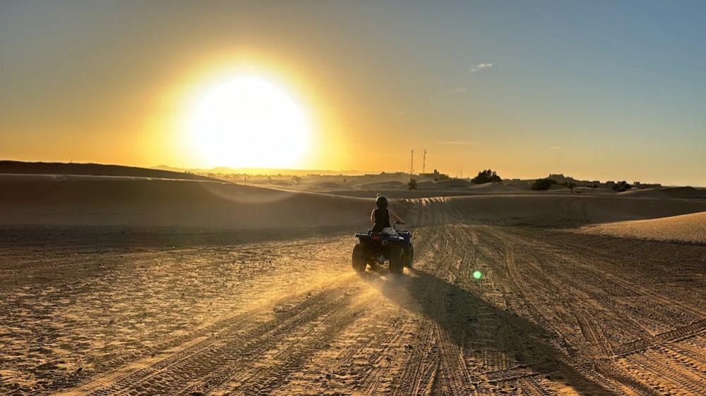 Quad rider silhouetted against the setting sun in the Merzouga desert