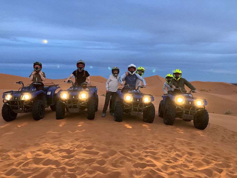 Pilotos en quads con los faros encendidos al anochecer en las dunas de Merzouga
